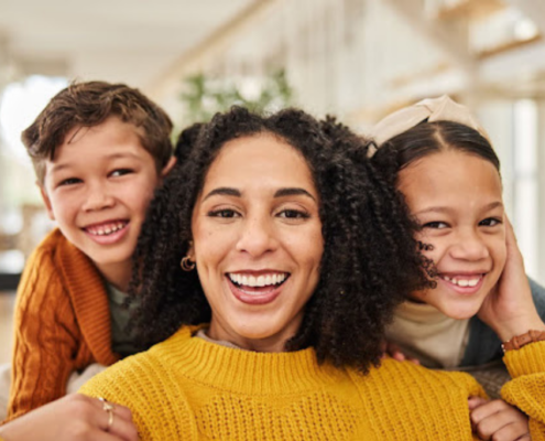 a smiling mom hugs her two smiling kids who are happy because they're using stress management tips