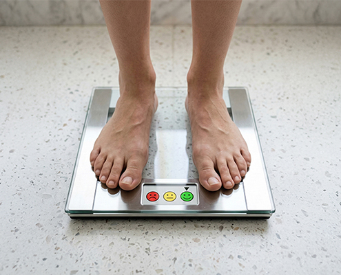 image of two feet standing on a scale where the display is pointing to a smiling green happy face icon
