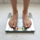 Person standing on a digital bathroom scale, representing weight management and healthy weight loss.