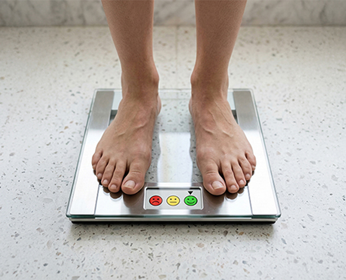 Person standing on a digital bathroom scale, representing weight management and healthy weight loss.