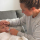 Parent checking a child's temperature with a thermometer while caring for them at home during an illness.