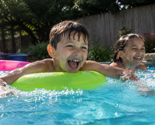 **Alt Text:** Children laughing and splashing together in a backyard swimming pool on a sunny summer day.