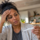 Woman checking her temperature with a digital thermometer while experiencing possible flu, COVID-19, or RSV symptoms at home.